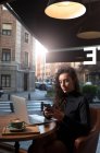 Молода жінка-підприємець використовує розумну поні, сидячи в кав'ярні. — стокове фото