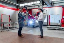 Male engineers discussing while robotics welding in factory — Stock Photo