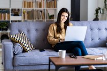 Smiling woman using laptop while sitting at home — Stock Photo
