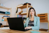 Smiling businesswoman working over laptop on desk in office — Stock Photo