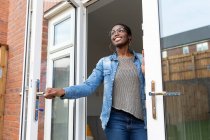Mujer sonriente abriendo puertas de casa - foto de stock