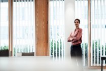 Confident female entrepreneur with arms crossed in office — Stock Photo