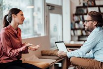 Femme entrepreneur discuter avec un collègue masculin sur tablette numérique au café — Photo de stock