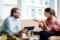 Empresaria explicando colega masculino mientras discute durante reunión en la cafetería - foto de stock