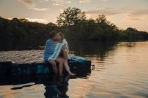 Молодая пара сидит на платформе для купания, целуется, завернутая в полотенце — стоковое фото