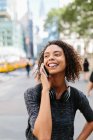 Jovem mulher saindo da língua enquanto fala no telefone inteligente na cidade — Fotografia de Stock