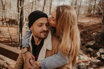 Girlfriend kissing on boyfriend's forehead in forest during autumn — Stock Photo
