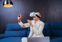 Businesswoman using virtual reality headset while sitting on sofa — Stock Photo