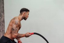 Без сорочки спортсмен тренування з мотузкою на стіні в спортзалі — стокове фото