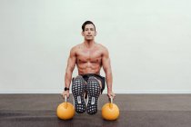 Deportista sin camisa que equilibra en kettlebell amarillo mientras que hace ejercicio en el gimnasio - foto de stock