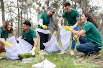 Улыбающиеся волонтеры собирают пластик в лесу — стоковое фото