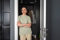Jeune femme souriante debout avec les bras croisés à la porte — Photo de stock