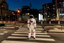 Male astronaut standing on zebra crossing during night — Stock Photo
