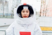 Serious female astronaut wearing space suit in city — Stock Photo
