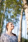 Jovencita sonriente disfrutando de la naturaleza en un bosque - foto de stock