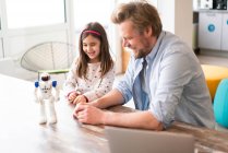 Smiling father and daughter looking at robot toy on table — Stock Photo