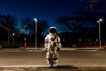 Young female astronaut in space suit standing on footpath at night — Stock Photo