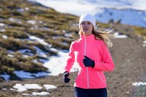 Young sportswoman running on mountain during winter on sunny day — Stock Photo