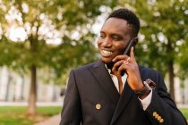 Sorridente giovane uomo che parla su smart phone al parco — Foto stock