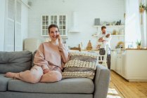 Femme souriante parlant sur le téléphone intelligent tandis que l'homme portant fille à la maison — Photo de stock