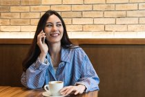 Junge Frau schaut weg, während sie in Bar mit Handy telefoniert — Stockfoto