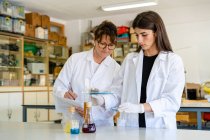 Scienziata matura con documento esaminando chimica con collega in laboratorio — Foto stock