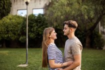 Pareja feliz de pie cara a cara en el césped - foto de stock