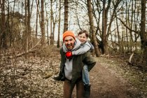 Lachender Vater gibt Sohn Huckepack-Fahrt im Wald — Stockfoto