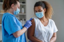 Кучеряве волосся жінка отримує вакцину в медичній клініці — стокове фото