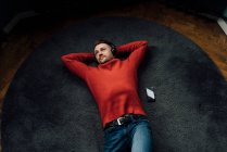 Maschio professionale sognare ad occhi aperti mentre si riposa sul tappeto sul posto di lavoro — Foto stock