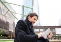 Усміхнений бізнесмен користується цифровим планшетом у офісному парку. — стокове фото