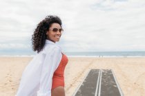 Sorrindo jovem mulher usando óculos de sol na praia — Fotografia de Stock