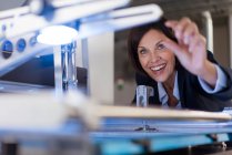 Smiling businesswoman analyzing machinery at illuminated industry — Stock Photo