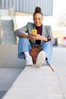 Young businesswoman using smart phone while sitting on retaining wall — Stock Photo