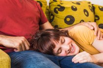 Smiling woman with eyes closed relaxing on boyfriend's lap in living room — Stock Photo