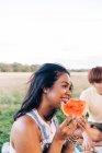 Donna sorridente che tiene fetta di anguria durante il picnic al parco — Foto stock