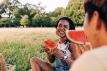 Amici sorridenti che mangiano anguria durante il picnic al parco — Foto stock