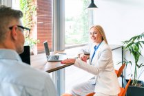 Female professional with laptop looking at male colleague while discussing in office — Stock Photo