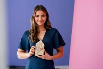 Giovane architetto donna con modello di casa di fronte alla parete multicolore — Foto stock