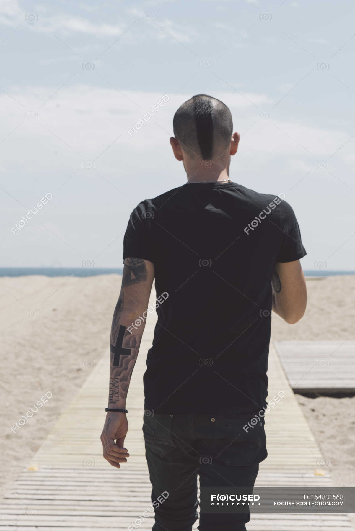 Back View Of Young Man With Mohawk Haircut And Tattoos Walking On