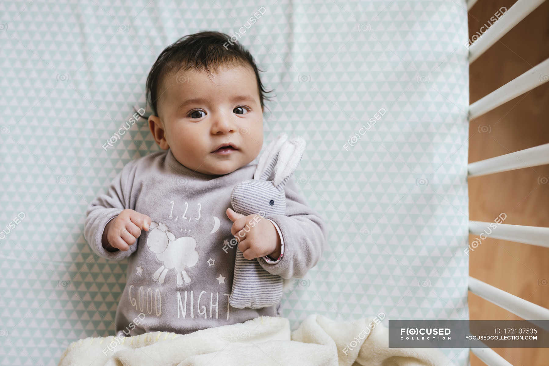 Cute Baby Girl Lying In Crib Holding Stuffed Rabbit Childhood