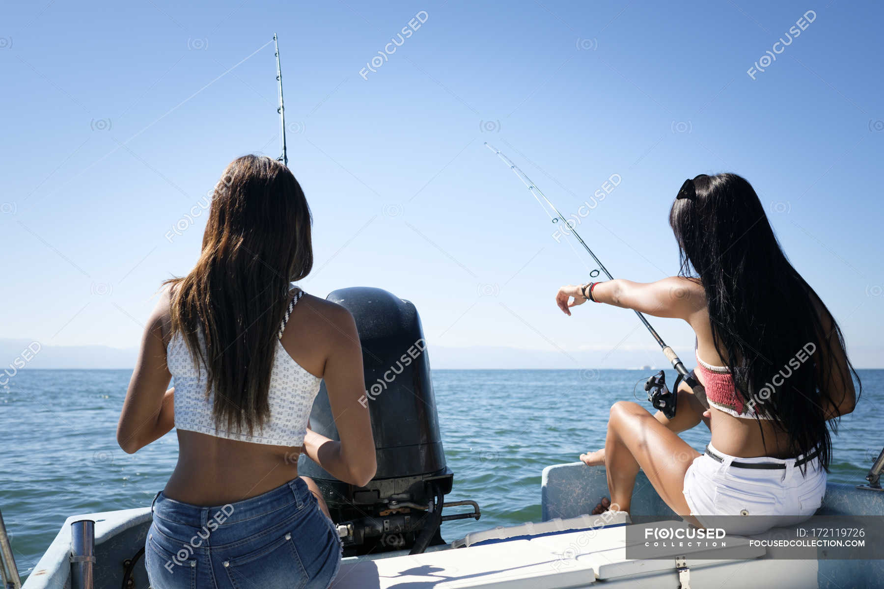 Two young women fishing on a boat trip — day, dark hair - Stock Photo |  #172119726