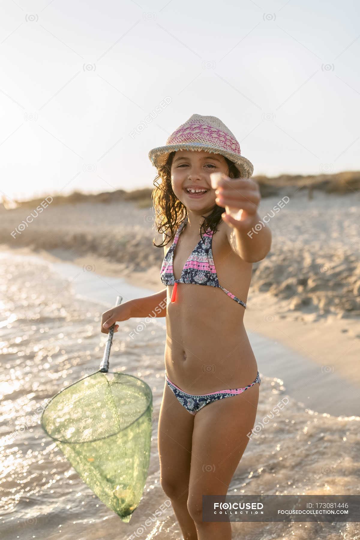 little girls what little girl eat a cookie on the beach, note shallow depth of ...