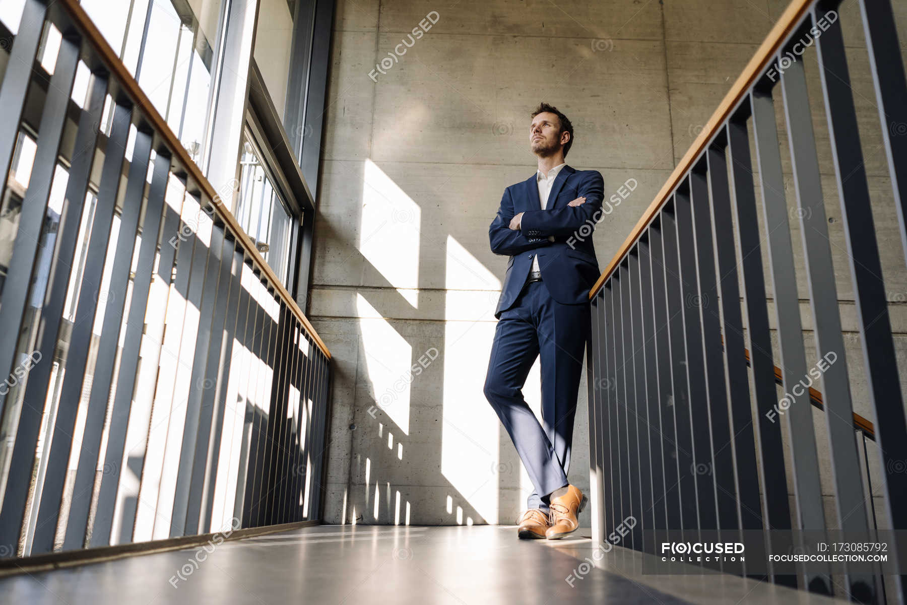 Поднимается снизу вверх. Человек в костюме на лестнице. Мужчина стоит на лестнице. Человек в костюме ракурс. Человек стоящий на лестницы.