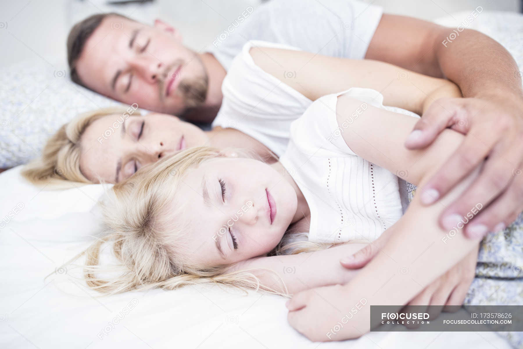 cuddling-family-sleeping-together-in-bed-arm-around-domestic-life