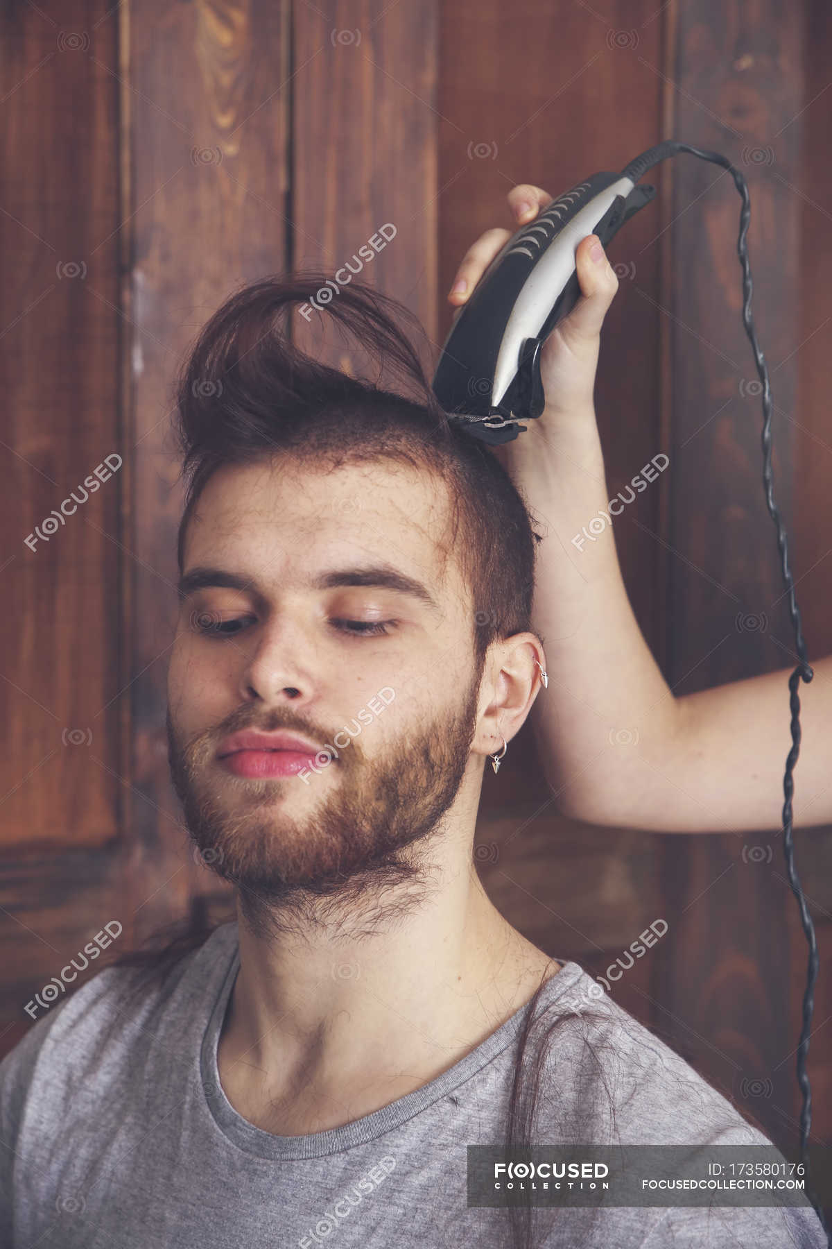 Portrait of young man getting a haircut by his girlfriend with hair cutting  machine — beard, quiff - Stock Photo | #173580176