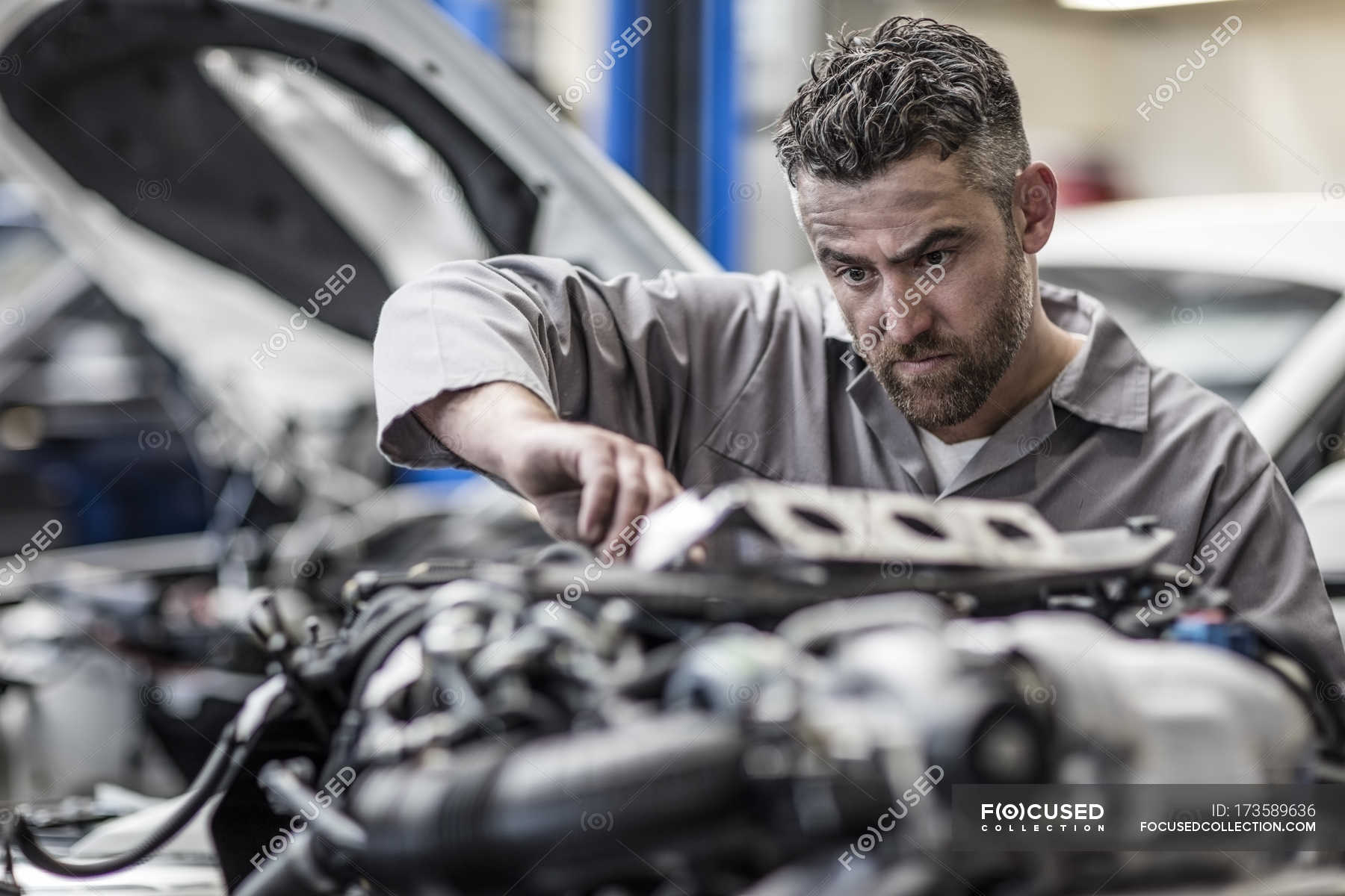 Car mechanic in a workshop working on engine — repair, overall - FocuseD 173589636 Stock Photo Car Mechanic Workshop Working Engine