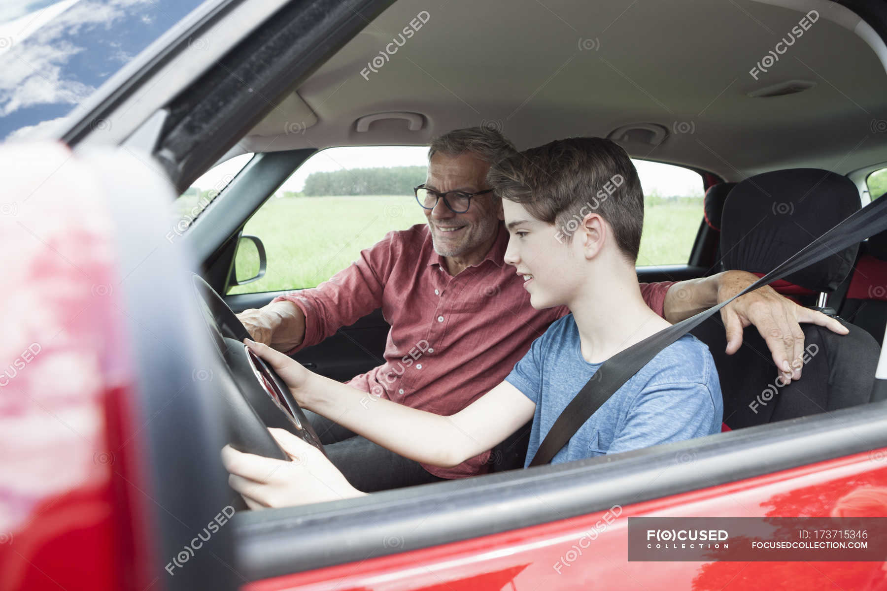 father-teaching-son-driving-car-together-steering-stock-photo