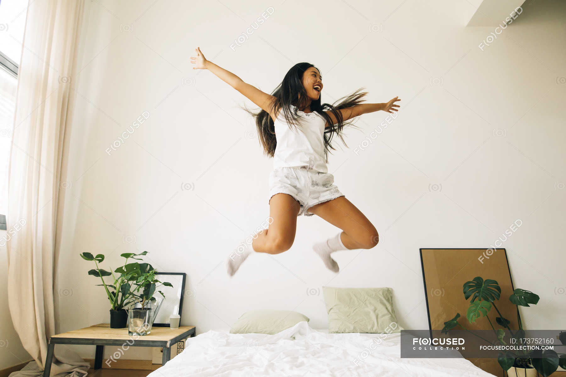 woman-jumping-on-bed-joy-jump-in-the-air-stock-photo-173752160