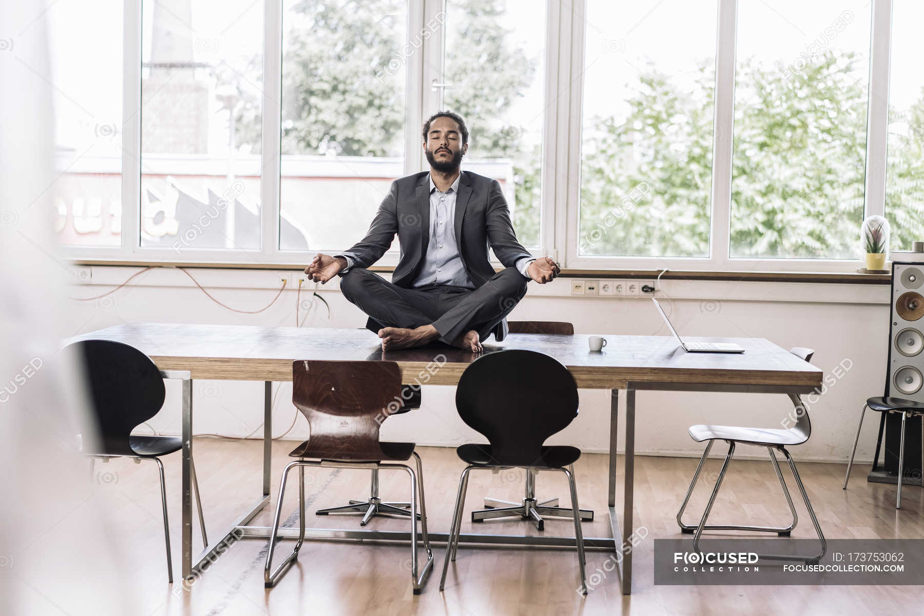 Businessman Sitting Cross Legged On Desk Cross Legged Full